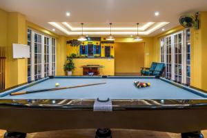 a pool table in a living room with yellow walls at TRIPLE Riverside Villa Hotel HoiAn in Hoi An