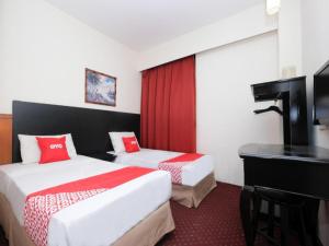 a hotel room with two beds and a desk at OYO 89968 Sri Sutra Hotel in Kepong Cubitt Forest Village