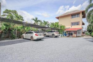 two cars parked in a parking lot in front of a building at Prickhom Garden Hotel in Nakhon Si Thammarat
