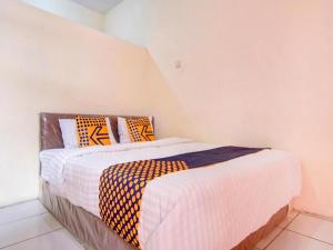 a bedroom with two beds with orange and white pillows at Hotel O Nakula Sadewa in Areman +56 photos