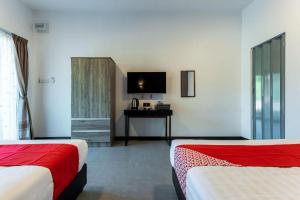 a hotel room with two beds and a television at OYO 90149 Pua Family Semporna in Bulingisan
