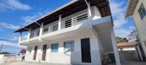 a white house with a balcony on top of it at Descanse na Praia de Fora in Palhoça