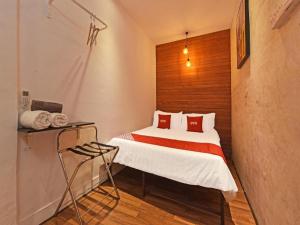 - une petite chambre avec un lit et des oreillers rouges dans l'établissement OYO 90662 The 1975 Hotel, à Kampong Bukit Ubi