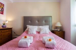 a bedroom with a pink bed with two white pillows at Apartamento Cardoso in Albufeira