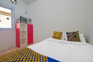 a bedroom with a white bed with yellow and blue pillows at SPOT ON 91993 Pondok Hs Padalarang Syariah in Bandung