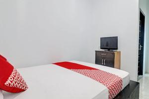 Bett mit roten und weißen Kissen und einem TV in der Unterkunft Hotel O Al-razzaq Guest House in Jambi + 45 Fotos