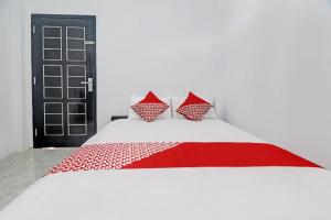 einem roten und weißen Bett mit zwei Kissen darauf in der Unterkunft Hotel O Al-razzaq Guest House in Jambi