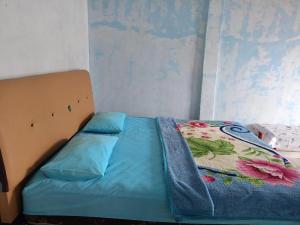 un lit avec une couette bleue avec un motif floral dessus dans l'établissement Hotel O Puri Azzura Danau Ranau Near Danau Ranau Pusri, à Jepara