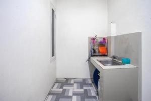 a small white kitchen with a sink and a window at Hotel O Almahyra Guest House Syariah in Sultan Thaha Airport