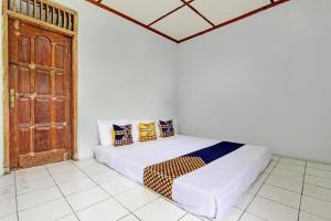 a bedroom with a bed in a room with an open door at SPOT ON 93592 Pondok Backpackers Ardafa Jogja in Manisrenggo