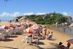 un groupe de personnes assises sur une plage avec des parasols dans l'établissement Suites BrisaMar, à Cabo Frio