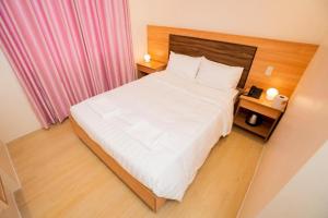 a bedroom with a large white bed and a pink curtain at JVJ HOTEL in Batangas City