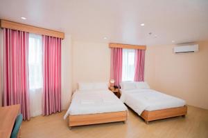 two beds in a room with red curtains at JVJ HOTEL in Batangas City