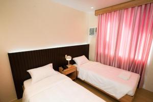 a bedroom with two beds and a window with pink curtains at JVJ HOTEL in Batangas City +3 photos