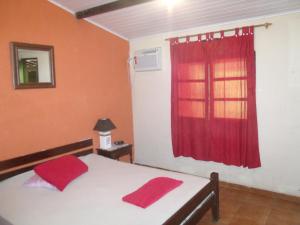 une chambre avec un lit avec des oreillers rouges dessus dans l'établissement Suites BrisaMar, à Cabo Frio