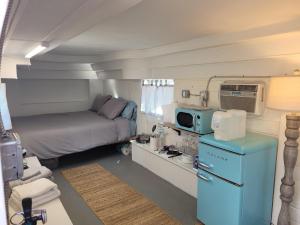 ジョシュア・ツリーにあるOne-of-kind Airstream for Your Desert Getaway!のベッド1台、青い冷蔵庫が備わる小さな客室です。