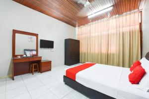 Un dormitorio con una cama, un escritorio y un televisor. en OYO 91052 Hotel Kenangan, en Kuala Terengganu