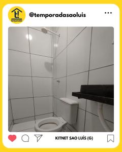 a bathroom with a toilet in a white tiled room at Kitnet São Luís - Studio G in São-José-do-Ribamar