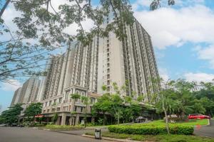 a large building on a city street with a tree at OYO 94080 Apartemen Podomoro Golf View Palito in Tjikuda Tiga