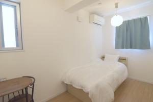 a white bedroom with a bed and a table at The No10 Miyako Resort in Miyako-jima