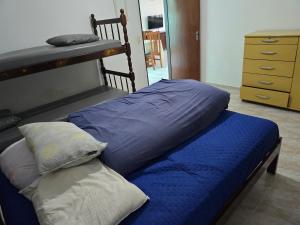 a bed with a blue blanket and two pillows at Peruíbe lazer in Peruíbe