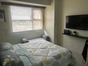 een slaapkamer met een bed en een flatscreen-tv bij Cozy and Affordable Studio Unit in Cebu City