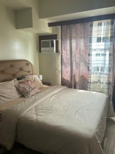 een slaapkamer met een wit bed met een raam bij Cozy and Affordable Studio Unit in Cebu City +2 foto's