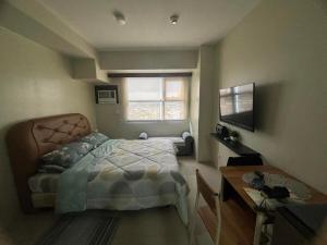 een slaapkamer met een bed, een bureau en een raam bij Cozy and Affordable Studio Unit in Cebu City