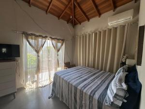a bedroom with a bed and a large window at 1Km Beach Curral Air-conditioning Nos 5 Bedrooms in Ilhabela