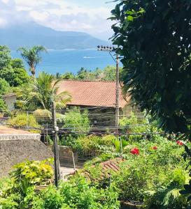 a house with a garden and a view of the ocean at 1Km Beach Curral Air-conditioning Nos 5 Bedrooms in Ilhabela