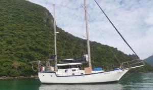 a white sail boat in the water with a mountain at Mekkala marasri in Ko Chang