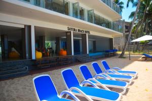 a row of blue beach chairs in front of a building at Sayura Beach Hotel in Unawatuna