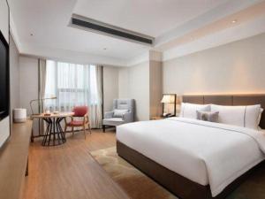 a bedroom with a large white bed and a table and chair at E-Cheng Hotel Shenyang North Railway Station in Shenyang +240 photos