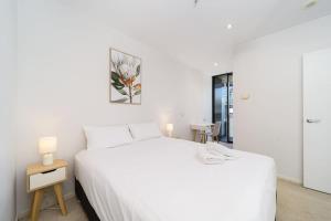 a white bedroom with a white bed and a table at 2Br2B1Ba Spacious apt with free parking Docklands in Melbourne +22 photos