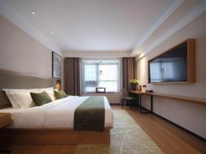 a hotel room with a bed and a flat screen tv at GreenTree Inn Luoyang Railway Station Wangfujing Wangcheng Park in Luoyang