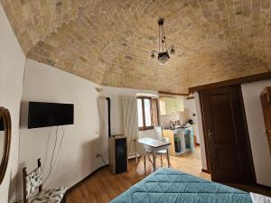 a room with a bed and a television and a kitchen at Piazzetta Del Forno - Monolocale in Assergi