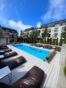 - une piscine avec chaises longues et un bâtiment dans l'établissement Malūno Vilos 1M7, à Palanga