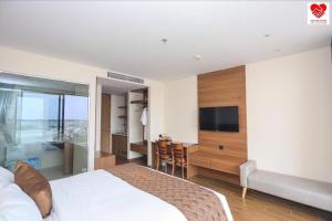 a bedroom with a bed and a kitchen and a television at Victor Group - Sam Sam Phu Yen Condotel in Phước Hậu