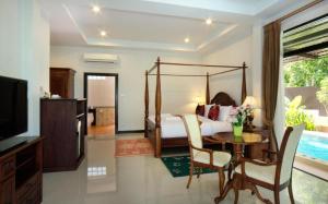 a bedroom with a bed and a table and a tv at Nattha Waree Hot Spring Resort and Spa in Ao Nang Beach