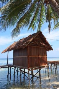 a hut in the water next to a palm tree at Kasumasa Homestay in Fambemuk