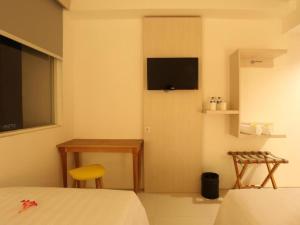 a bedroom with a bed and a television on the wall at Fovere Hotel Palangkaraya in Palangkaraya