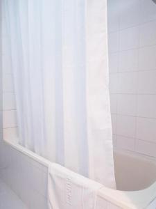 a bathroom with a white shower curtain and a tub at Dusit Hotel in Sakon Nakhon
