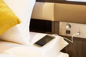 a cell phone sitting on top of a bed next to a laptop at HOTEL MYSTAYS Ueno East in Tokyo