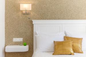 una camera da letto con un letto bianco con cuscini dorati di Adriani Hotel a Naxos Chora