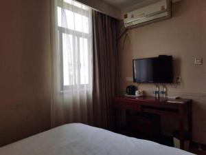 a bedroom with a bed and a desk with a television at Shell Hotel Shanghai Baoshan Meilanhu Luosheng Road in Luodian