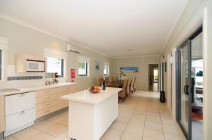 a kitchen with white cabinets and a dining room at CeeSpray - Accommodation in Huskisson - Jervis Bay in Huskisson