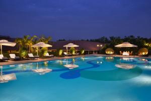 una gran piscina con sillas y sombrillas por la noche en Madhubhan Resort & Spa, en Anand
