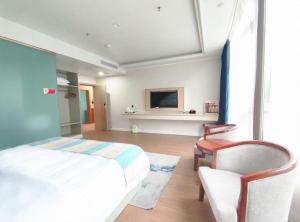 a bedroom with a bed and a chair and a tv at GreenTree Alliance Hotel Chongqing Qianjiang County Wuling Shui'an Jiaotong Xi Road in Qianjiang