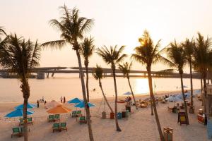 a beach with palm trees and chairs and umbrellas at Hillside Luxury Phu Quoc Apartment in Phu Quoc