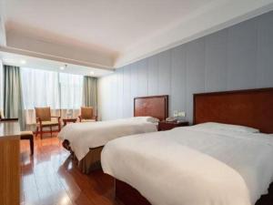 una camera d'albergo con due letti, un tavolo e delle sedie di GreenTree Inn JiangSu WuXi BinHu TaiHu Pearl Development Mansion Business Hotel a Wuxi
